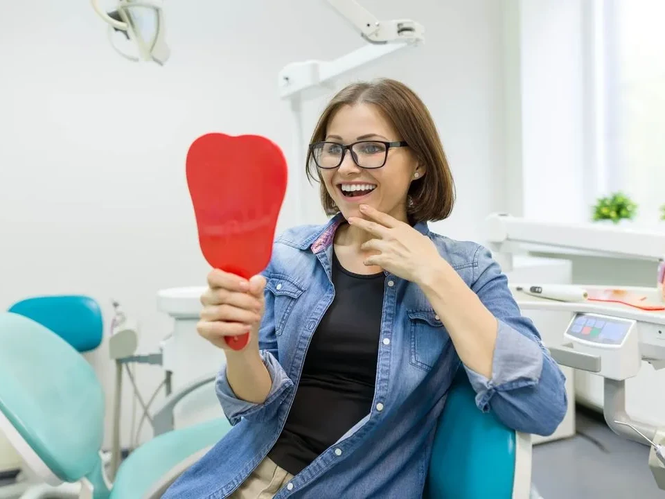 woman smiling at her white teeth after dental care at Cordova Dentures and Implants